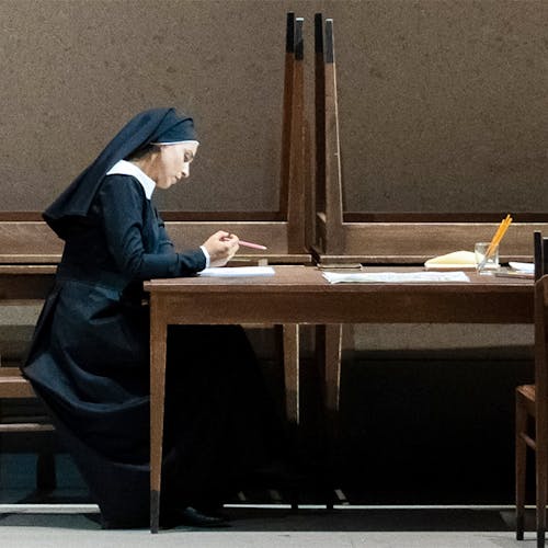A nun sitting at a table reading a piece of paper