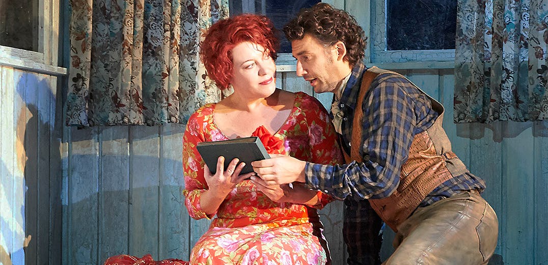 Two people sitting next to one another, holding a book