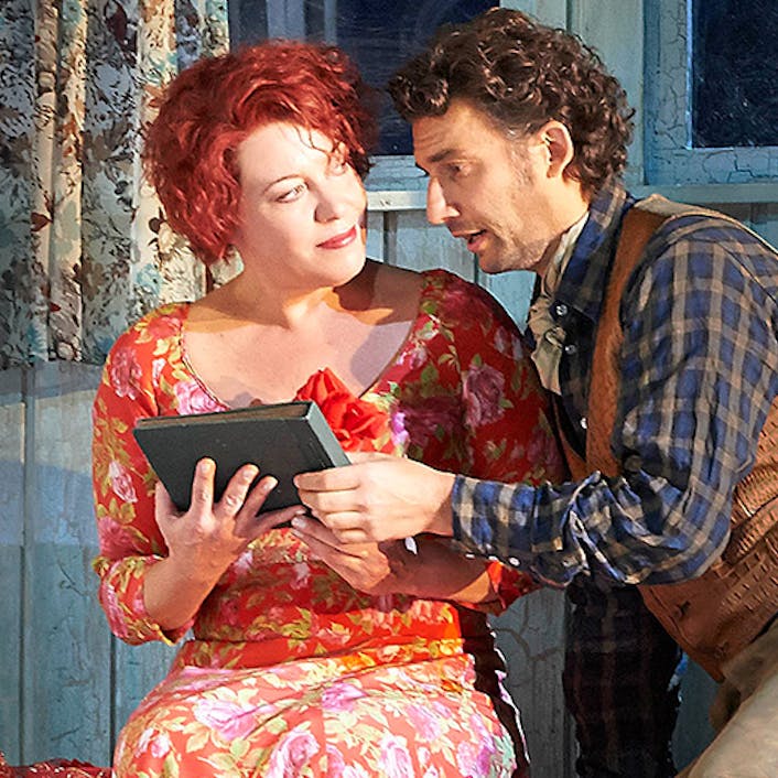Two people sitting next to one another, holding a book