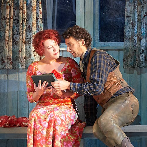 Two people sitting next to one another, holding a book