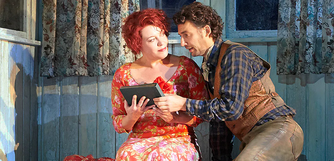 Two people sitting next to one another, holding a book