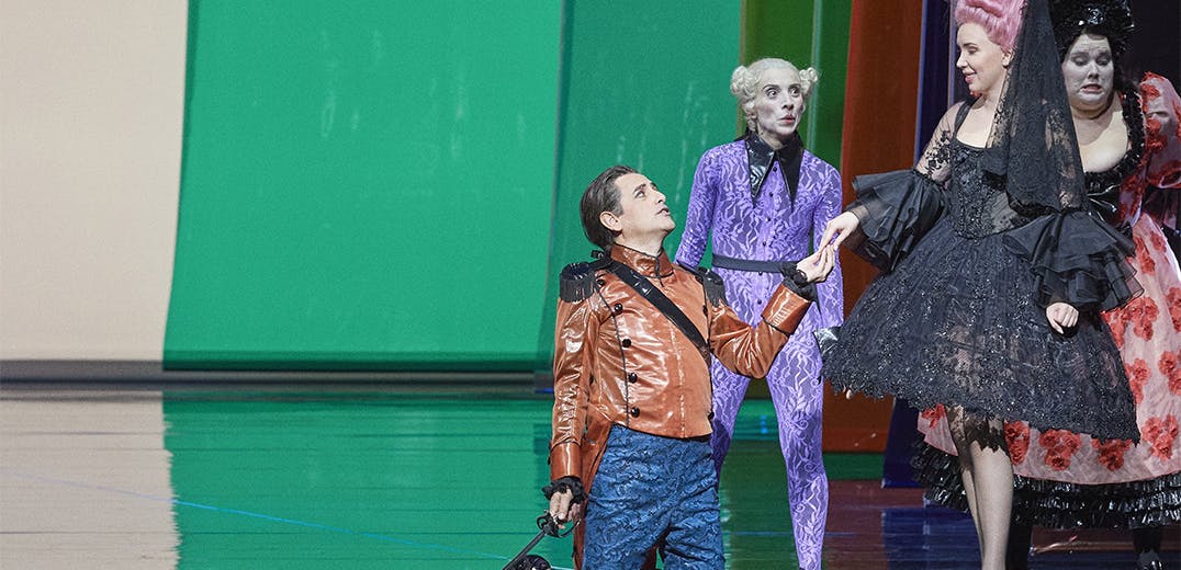 Juan Diego Flórez kneeling on staging, holding hands with a standing performer; two other performers stand around them.