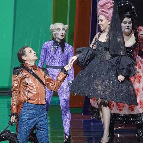  Juan Diego Flórez kneeling on staging, holding hands with a standing performer; two other performers stand around them.