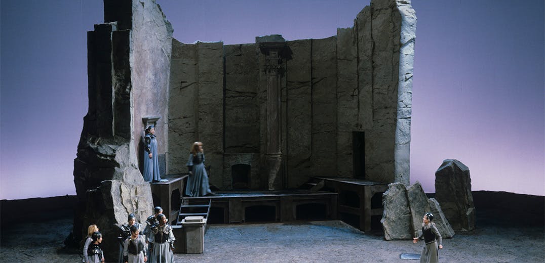A group of people standing around a large wall made of stone