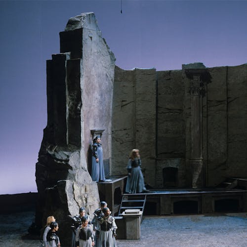 A group of people standing around a large wall made of stone