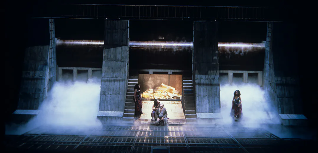 Four performers on a foggy stage in front of a vault of gold