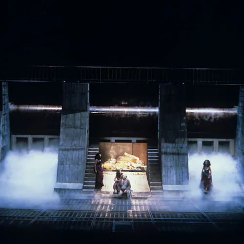 Four performers on a foggy stage in front of a vault of gold