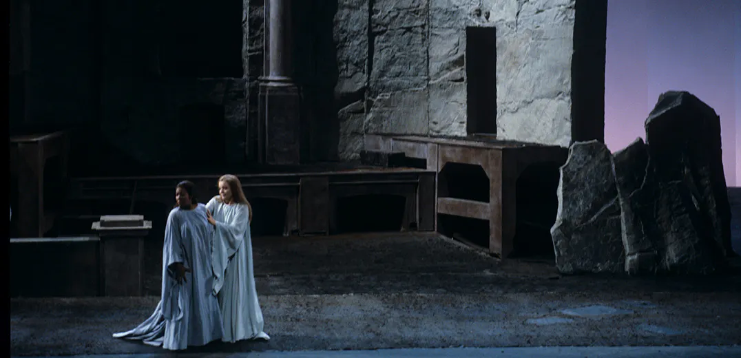Two performers standing in front of a large stone structure