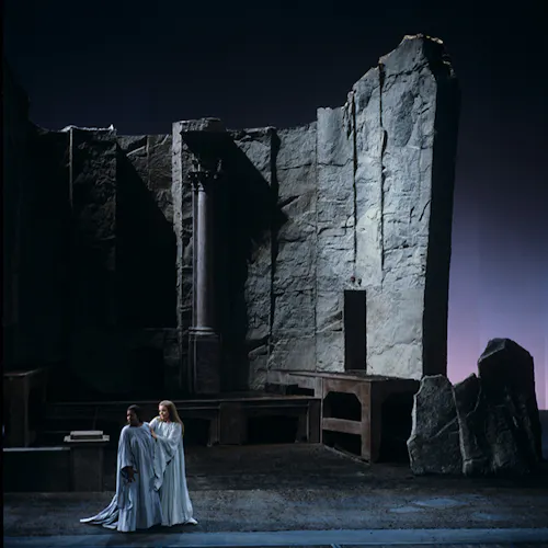 Two performers standing in front of a large stone structure